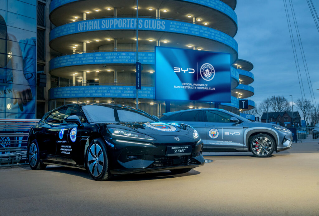 BYD partenaire officiel de Manchester City : véhicules électriques BYD devant l’Etihad Stadium avec branding du club
