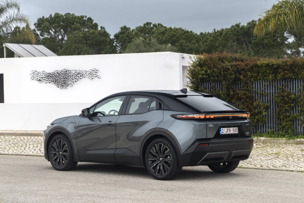 Toyota C-HR+ SUV électrique vue arrière avec bandeau lumineux sur route urbaine