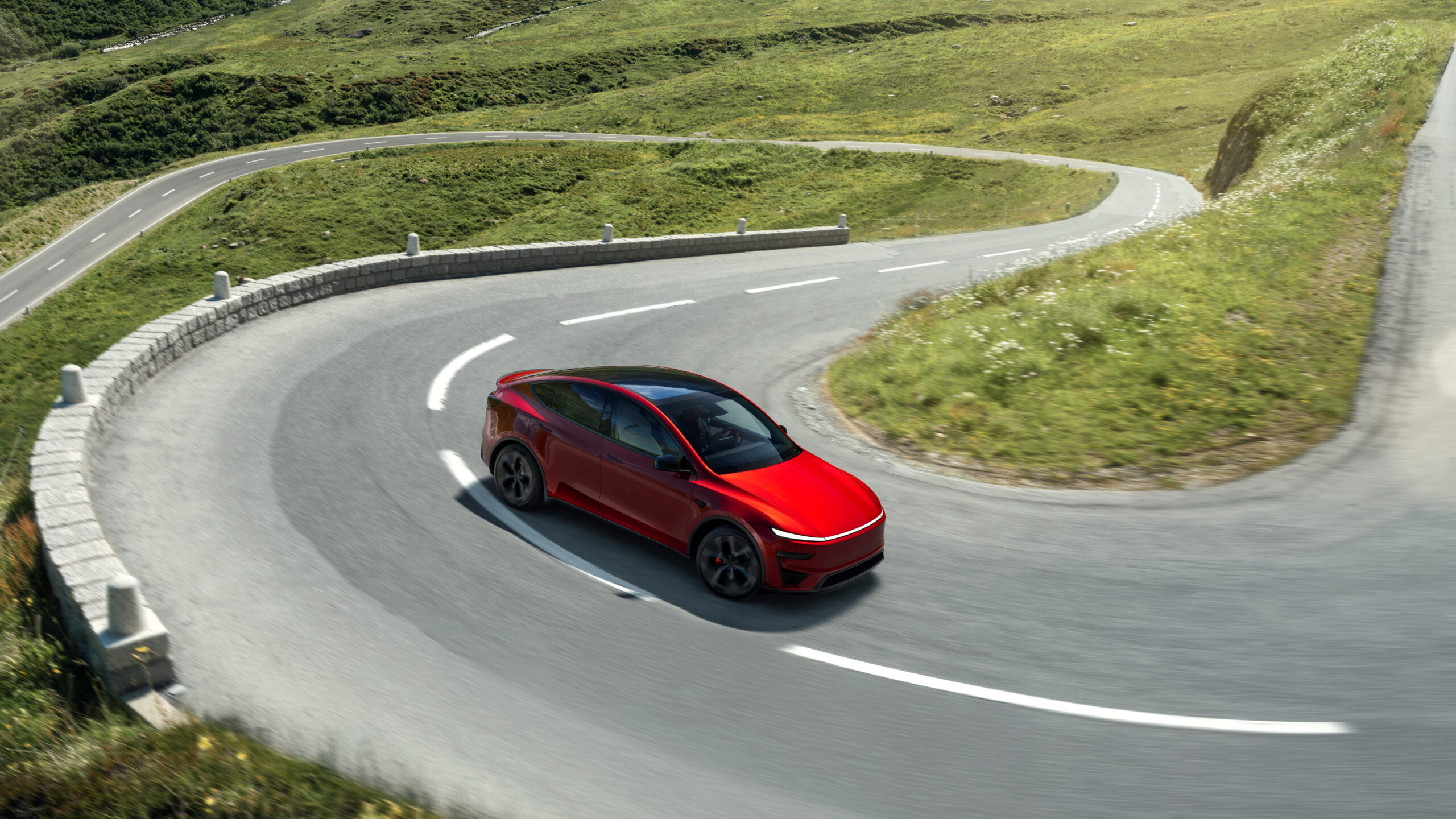 Tesla Model Y Performance rouge en virage sur route sinueuse en montagne