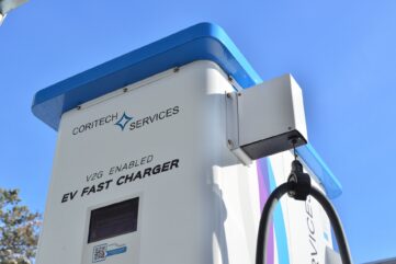 Borne de recharge rapide portant la mention V2G enabled, câble de recharge suspendu, photo d'illustration