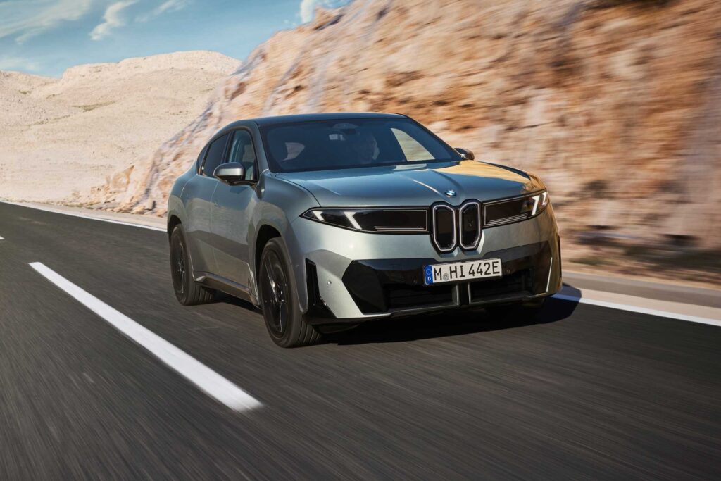 SUV coupé électrique gris-vert vu de trois quarts avant sur une route de falaise, avec sa double calandre fermée (photo constructeur)
