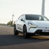 Polestar 4 blanche en roulage sur une route dégagée, avec des éoliennes en arrière-plan (photo officielle Polestar)