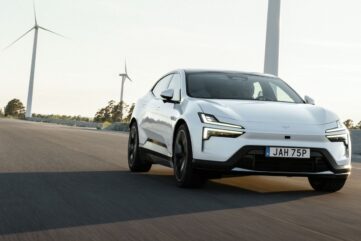Polestar 4 blanche en roulage sur une route dégagée, avec des éoliennes en arrière-plan (photo officielle Polestar)