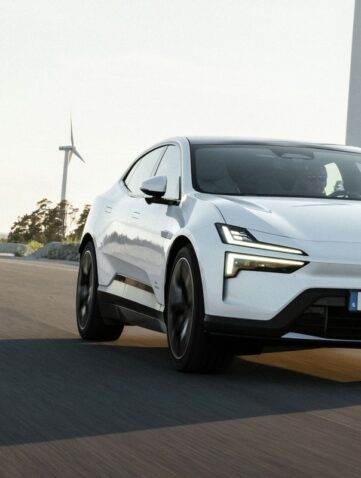 Polestar 4 blanche en roulage sur une route dégagée, avec des éoliennes en arrière-plan (photo officielle Polestar)
